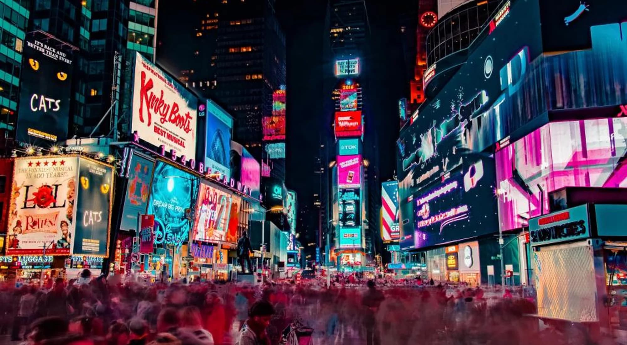 Digital billboards lighting a city avenue at dusk