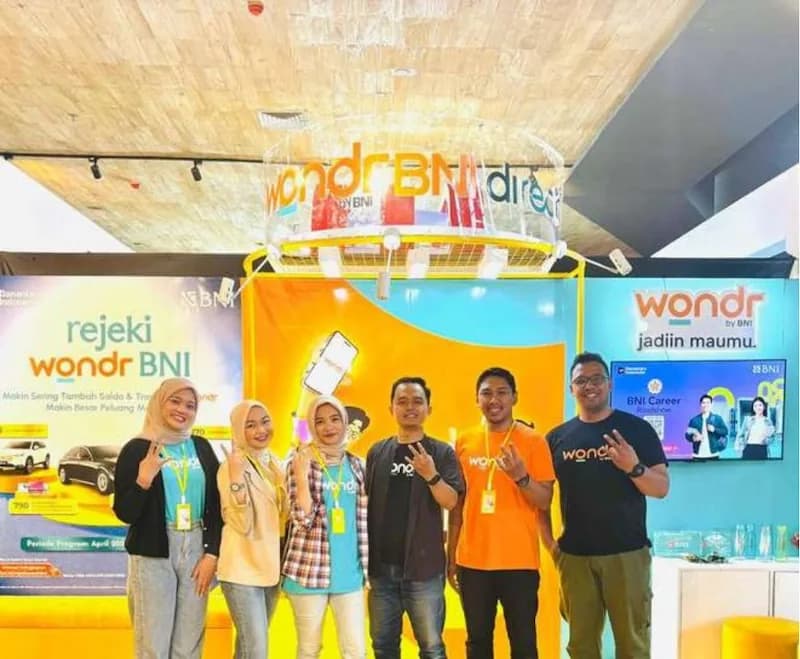 Tim aktivasi wondr by BNI berpose di booth pameran berwarna oranye