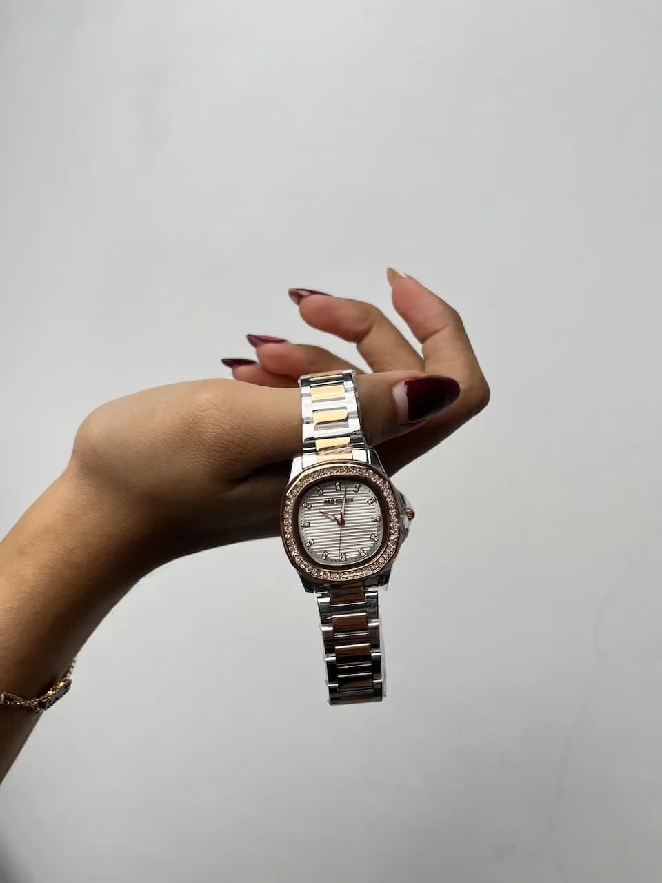 A two-tone wristwatch with a crystal bezel draped over a creator's hand