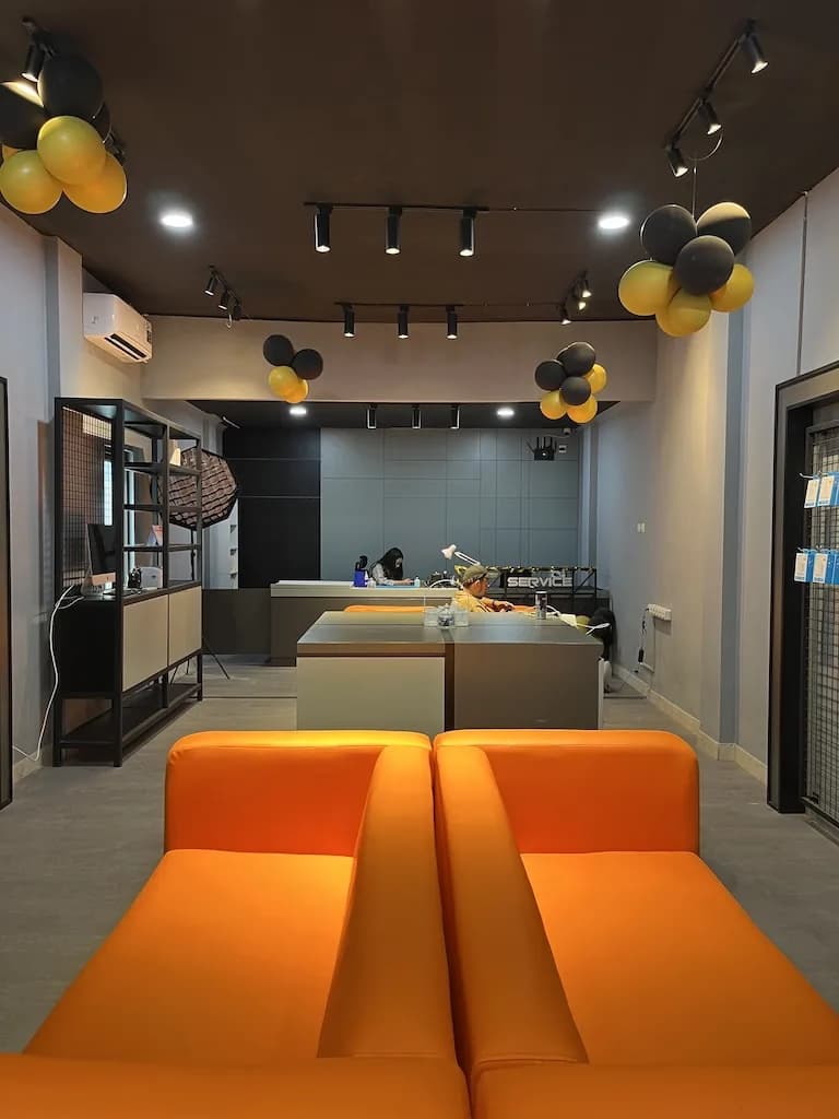 Lounge outlet dengan sofa oranye menghadap meja servis di bawah lampu track