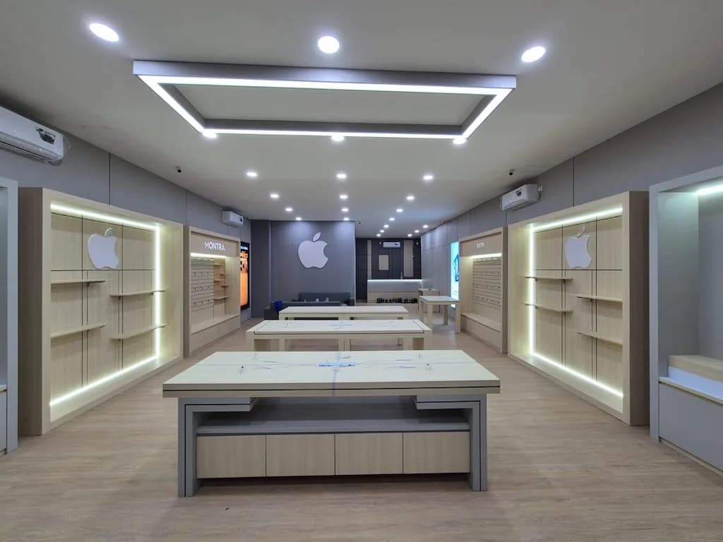 Lantai toko Apple yang simetris dengan dinding display kayu berlampu dan meja produk