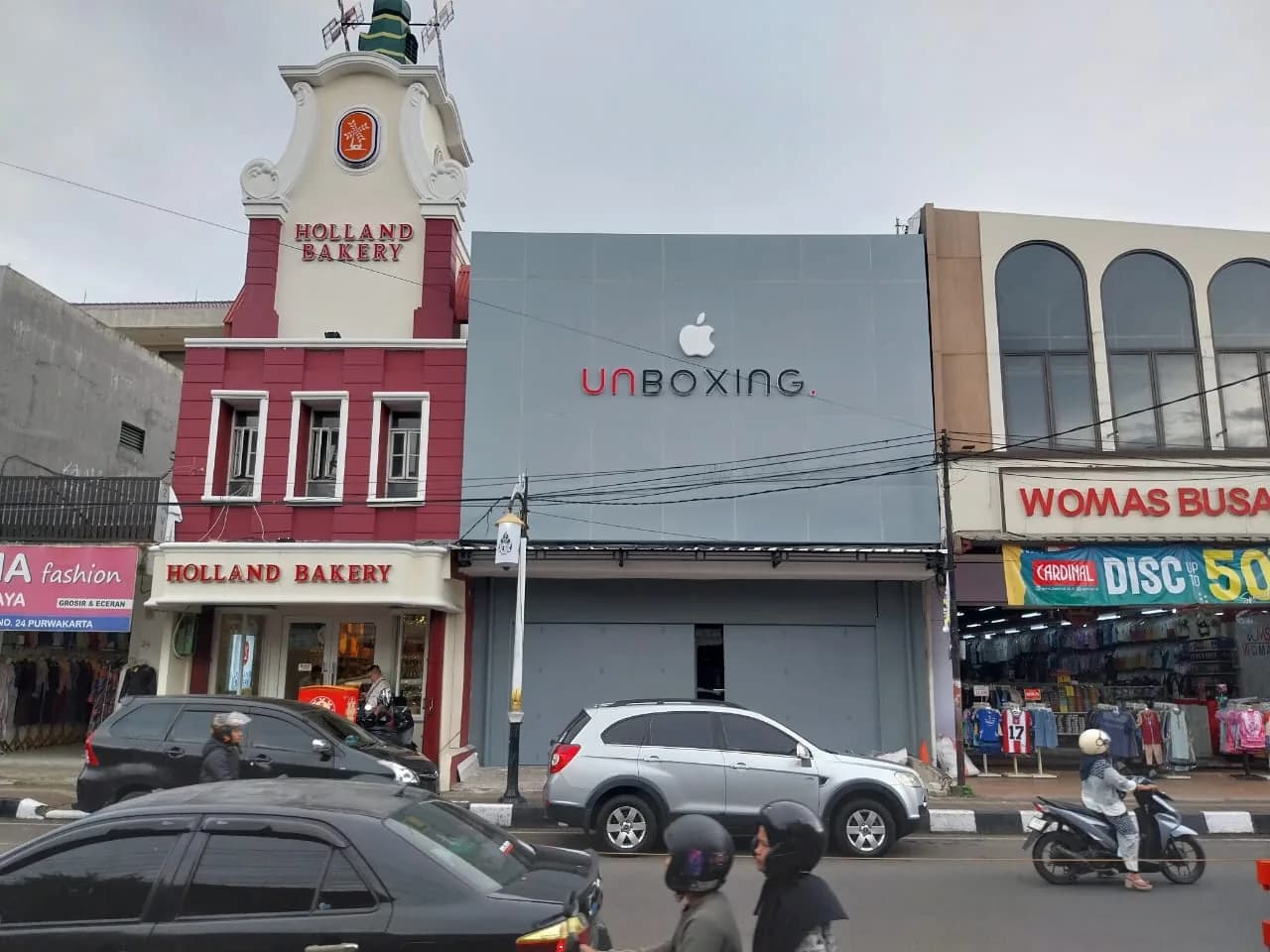 Fasad toko Unboxing dengan logo Apple di jalan pertokoan yang ramai