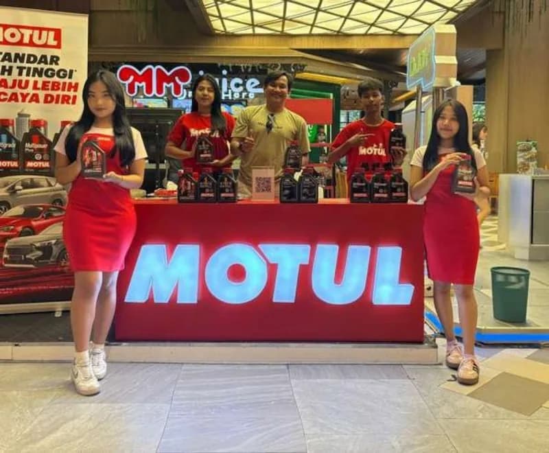 Brand ambassador Motul memegang botol oli di konter mal yang menyala